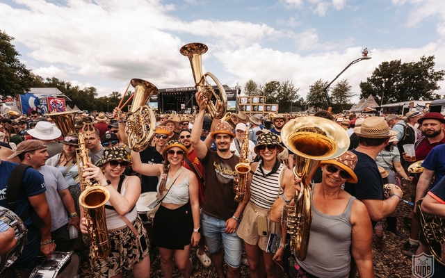 Menschen mit Blasinstrumenten auf einem Musikfestival im Freien.