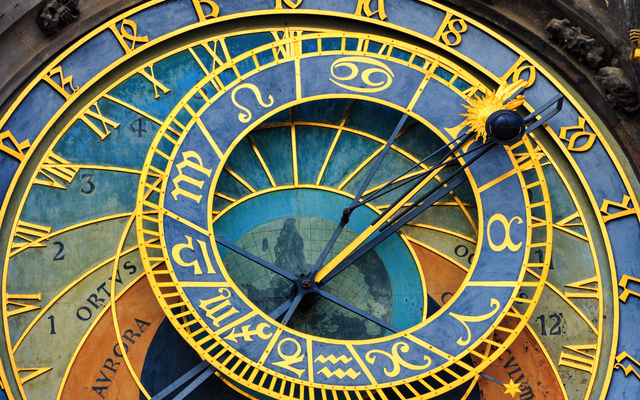 Nahaufnahme einer astronomischen Uhr mit Tierkreiszeichen und römischen Ziffern.