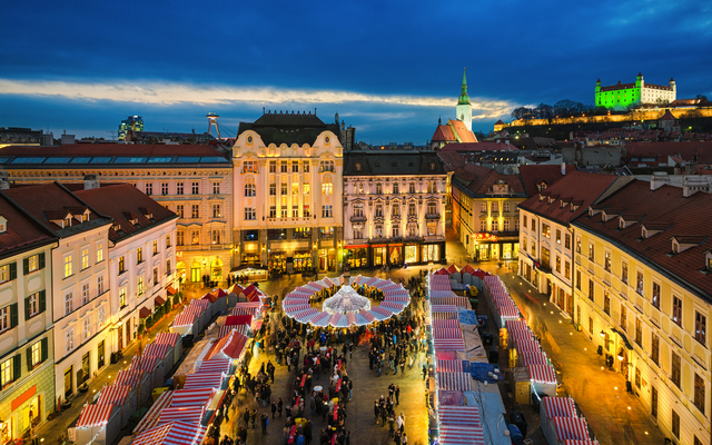 Luftaufnahme eines belebten Weihnachtsmarkts abends in einer historischen europäischen Stadt.
