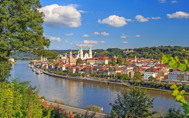 Stadtlandschaft mit Fluss und Kirche unter blauem Himmel