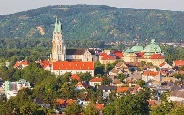 Städtelandschaft mit Kirche und grünen Hügeln im Hintergrund.