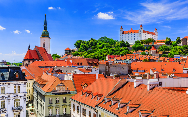 Blick auf Bratislavas Altstadt mit Burg und Kirche unter blauem Himmel.